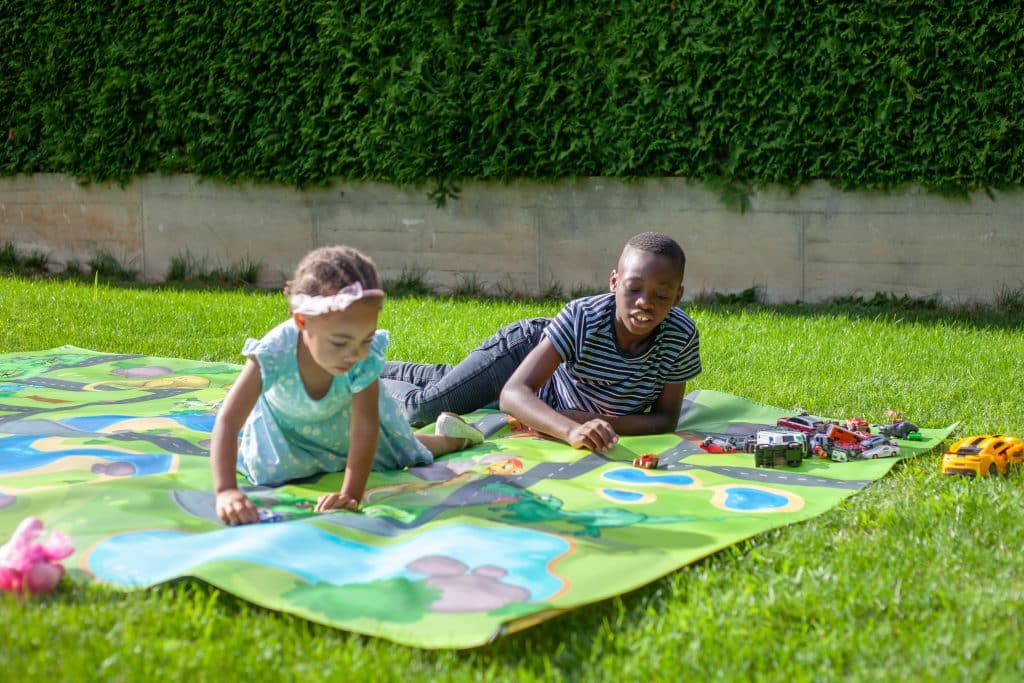 Kinder spielen auf Spielteppich Straße im Garten