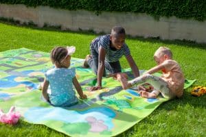 Kinder spielen begeistert auf Spielteppich Straße im Garten